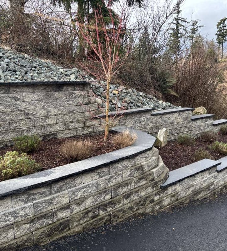 Tiered stone retaining wall with dark capstones in Oak Harbor