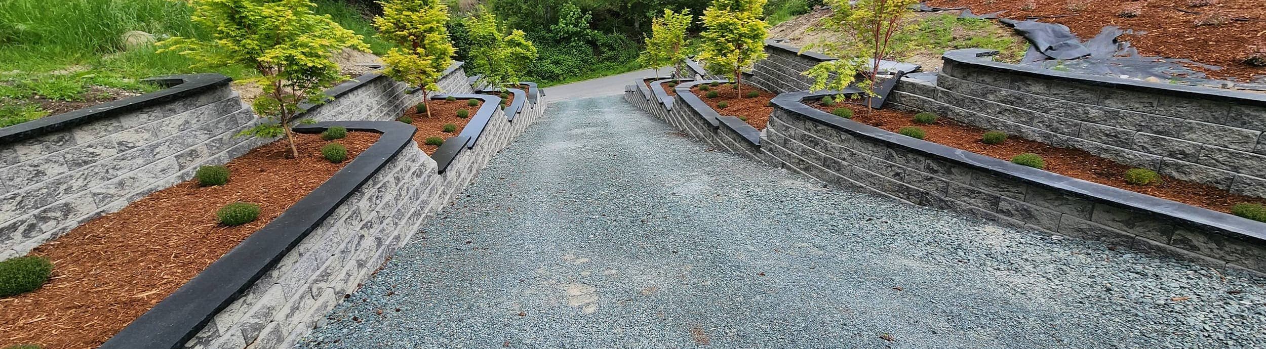 Gravel driveway lined with tiered stone retaining walls on Whidbey Island