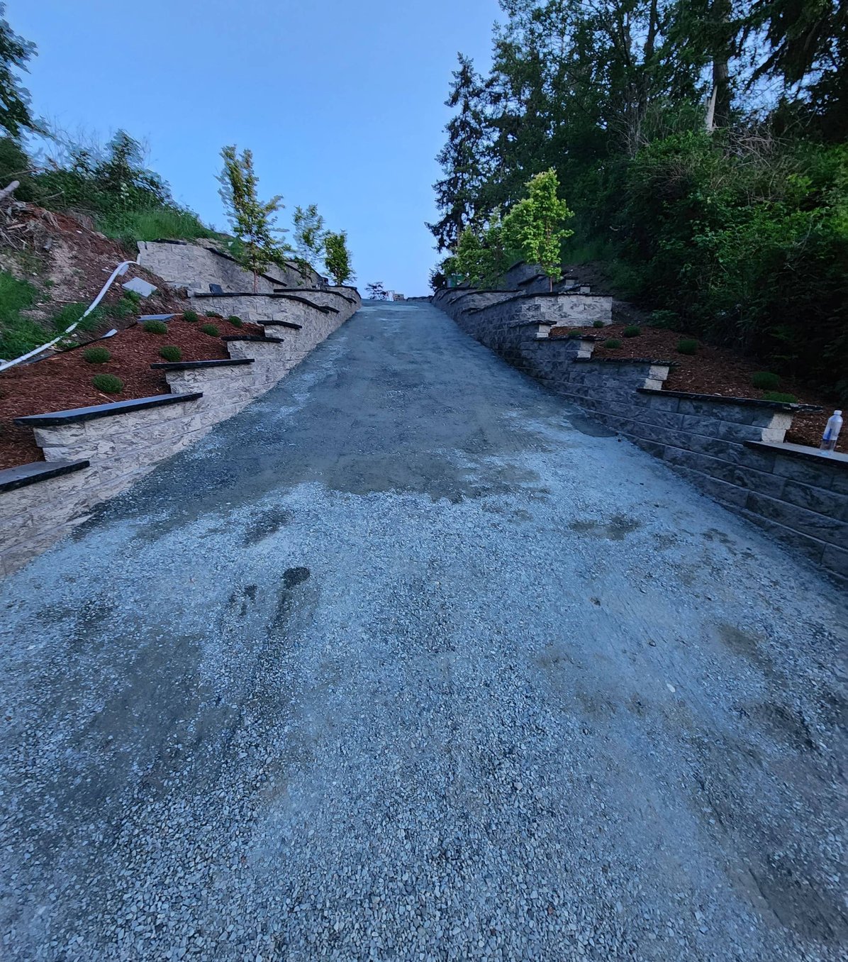 Uphill gravel drive with terraced block walls on Whidbey Island
