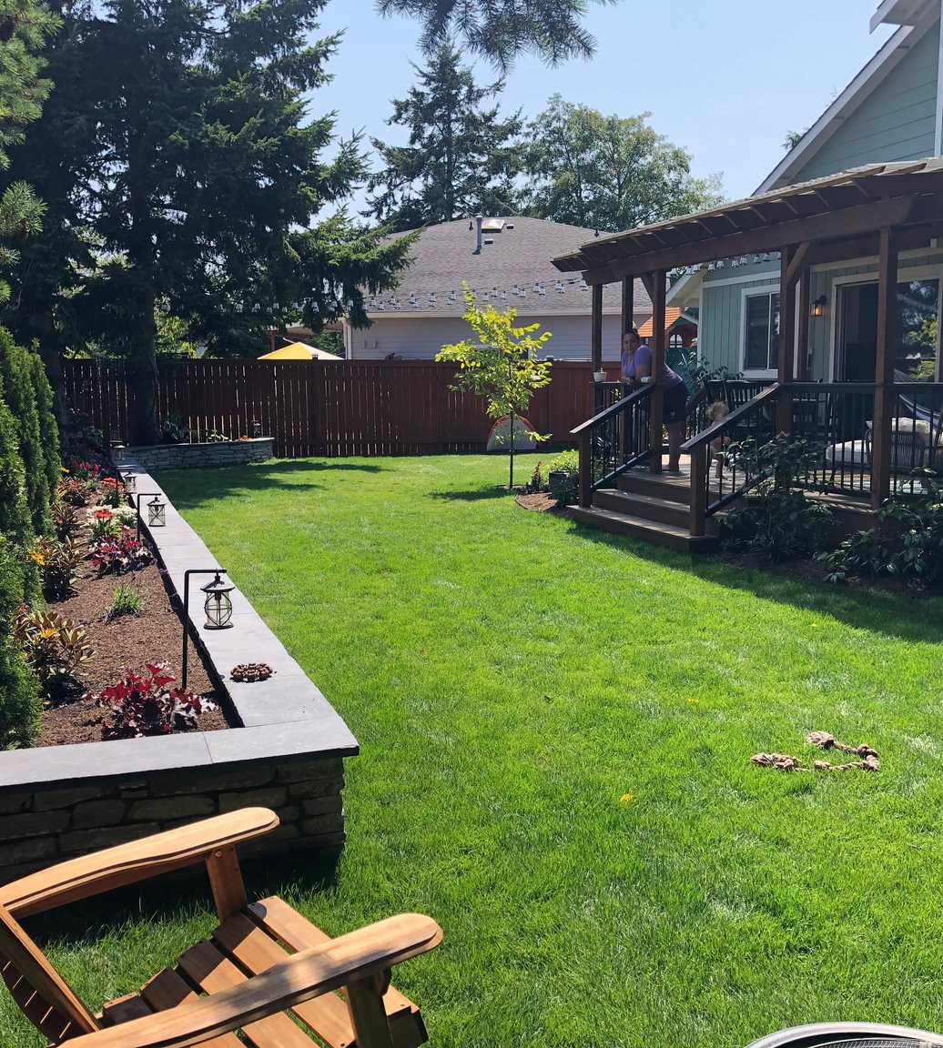 Landscaped Oak Harbor backyard with lawn, garden wall, and deck