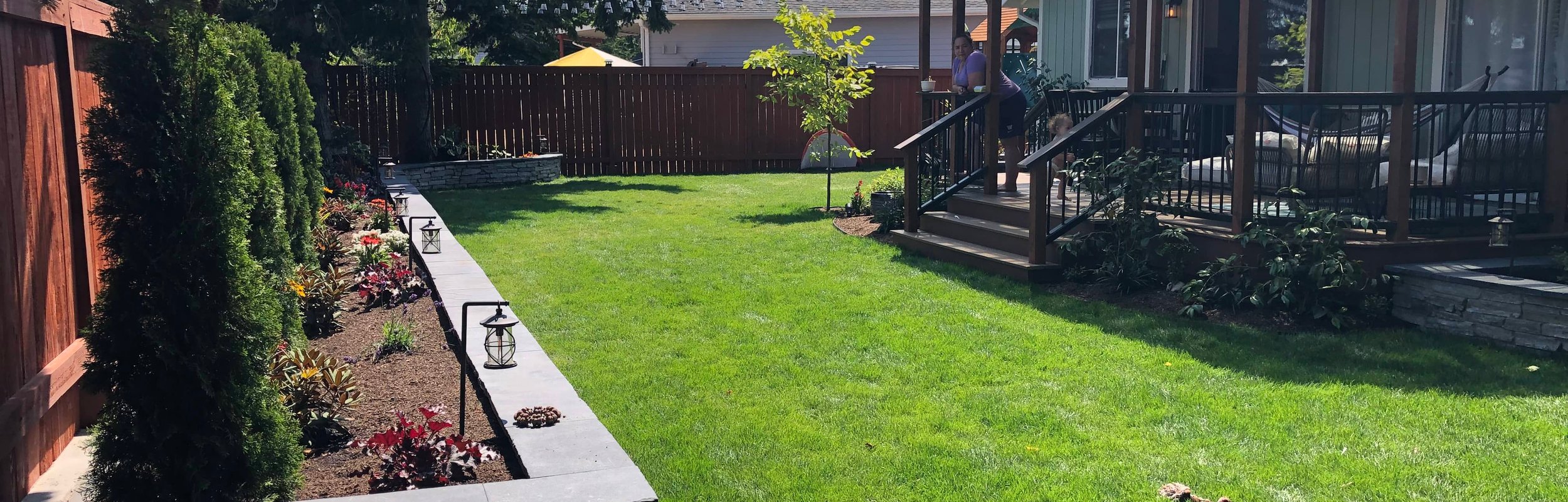 Landscaped Oak Harbor backyard with lawn, garden wall, and deck