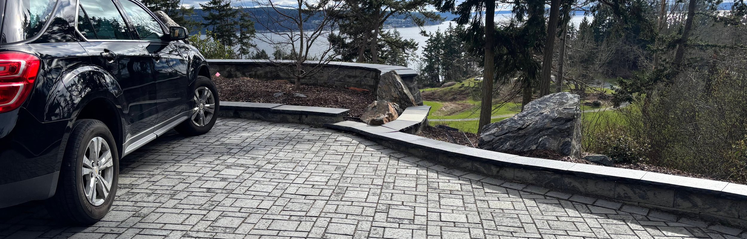 Gray paver driveway and stone wall overlooking the water on Whidbey Island